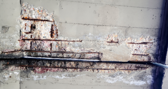 A close up view of concrete cancer, with the concrete peeling away to reveal the steel structure within rusting. Concrete cancer can reveal itself in apartment buildings and may need remedial work to be repaired.