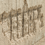 A close up of a wall with concrete cancer, where the steel structure supporting the concrete rusts, expands, and the concrete cracks and blows off in places. It can be expensive to correct.