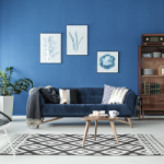 A living room with a blue wall, furnished to rent out on Airbnb. The blue couch, rug, coffee table, wall hangings, sideboard and rug have been purchased new and can be claimed for depreciation