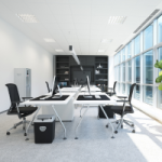 A small office with white walls with a full wall of windows with sun streaming through. There are white desks set up in the office, with black rolling chairs. Offices are a popular choice for property investors.