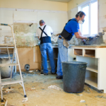 Two men demolish a kitchen in an investment property. Before ripping out an old kitchen, consider if there is any residual value left that can be claimed as Disposal of Capital Works