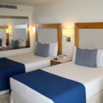 A motel room with twin beds and blue throws on the foot. A motel room is an example of where the Short Term Traveller Accommodation 4% Depreciation rate would apply.