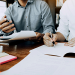 An accountant meets with his client in the office, reviewing paperwork, including details of an investment property purchased that requires a Tax Depreciation Schedule.