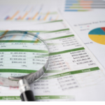 A magnifying glass sitting over financial reporting. The ATO is matching information from property management data to find property owners not reporting rental income correctly.